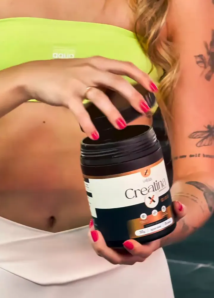 Pote de Creatina UniMax nas mãos de uma atleta